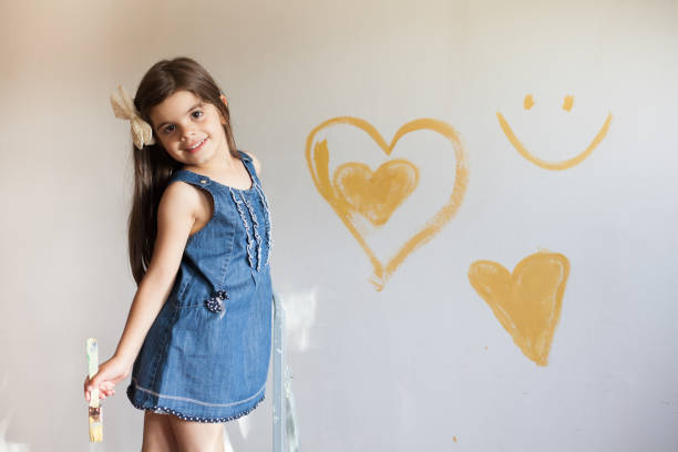 Sweet little girl painting wall stock photo