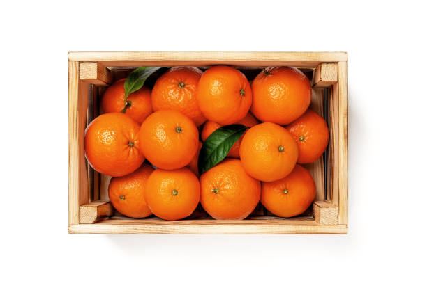 Sweet ripe orange tangerines in a wooden crate isolated on white background. Fresh citrus in a wood box. Eco-friendly rustic style containers for fruits and vegetables. Vegetarian and healthy eating. stock photo