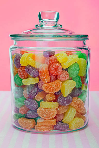 Sweets in a glass jar Sweets in a glass jar with a pink and white striped background. candy jar stock pictures, royalty-free photos & images