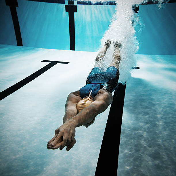 Swimmer diving after the jump in swimming pool Underwater shot of a swimmer diving after the jump in the swimming pool.   diving into water stock pictures, royalty-free photos & images