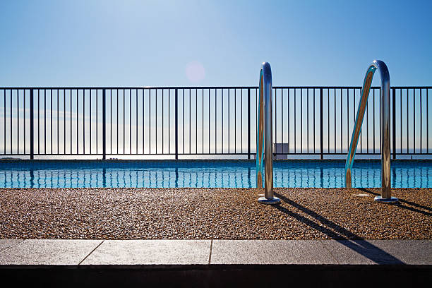 Swimming pool edge with ladder and sky background stock photo