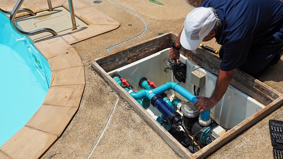 Technician fixing swimming pool water pump. Service and maintenance for swimming pool.