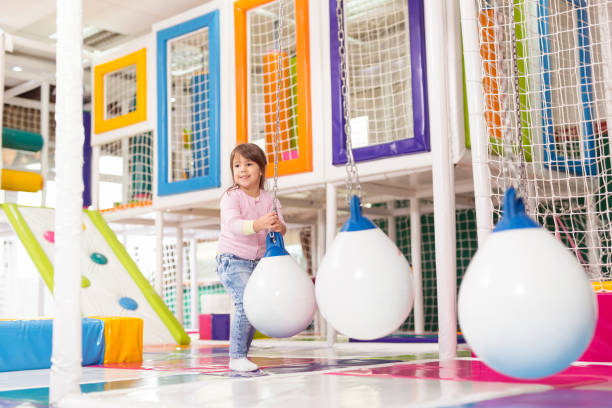 Swinging Young girl playing with the giant hanging balls in a colorful playroom, having fun indoor playground stock pictures, royalty-free photos & images