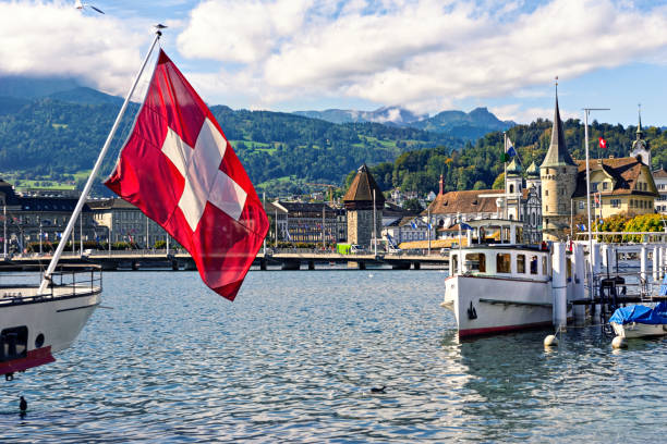 Swiss flag against background of historic center of Lucerne and Swiss Alps. Switzerland, Europe.