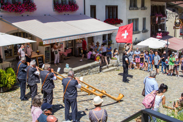 A Swiss musician group play the traditioanl music instrument alphorn with a flag bearer to swing the National flag stock photo