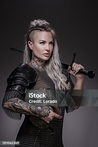 istock Sword wielding viking warrior blonde female in studio shot 1311042349
