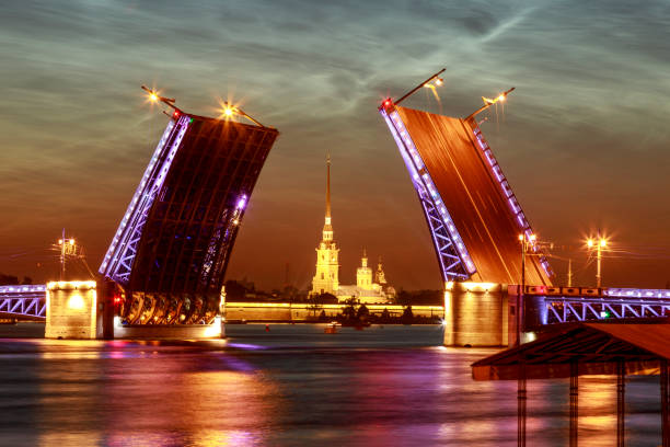 俄羅斯聖彼德堡的象徵。夏日白色的夜晚。在涅瓦河上舉起皇宮橋。水中照明的反射。 - vera pauw 個照片及圖片檔