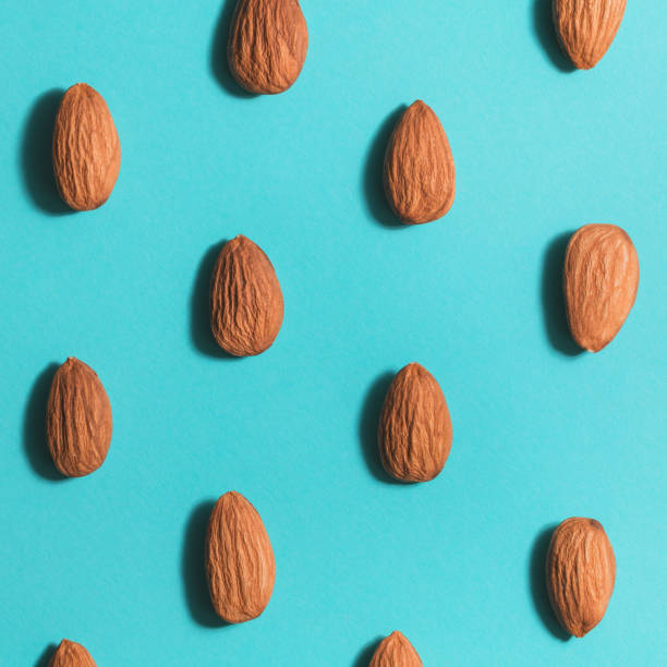 Symmetrical pattern of almonds on blue. Flat lay. Symmetrical pattern of almonds on blue. Flat lay. nut food stock pictures, royalty-free photos & images
