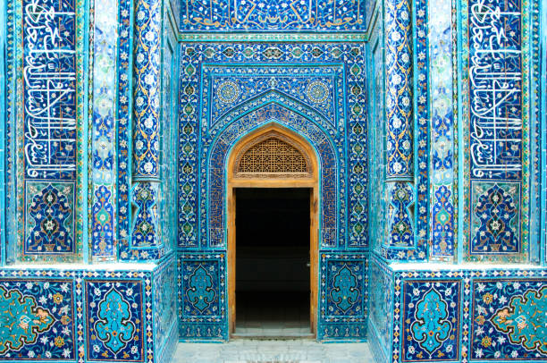 Symmetrical, richly decorated with blue ceramic islamic tiles, entrance and open door in Shah-I-Zinda Shah-I-Zinda is a famous architectural complex, necropolis in Samarkand, Uzbekistan silk road stock pictures, royalty-free photos & images