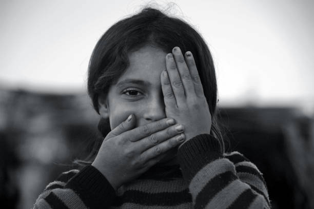 syrian girl showing one eye, mouth closed stock photo