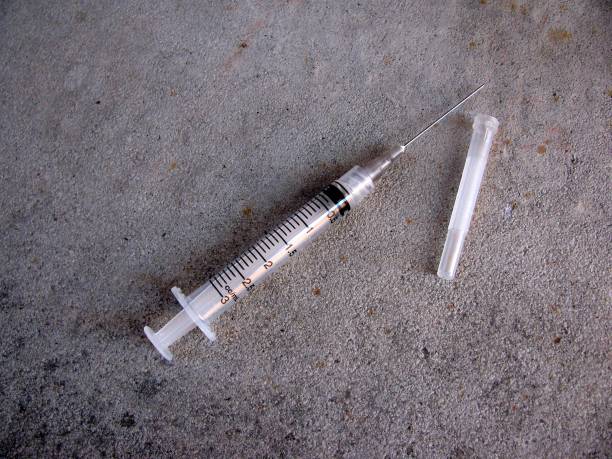 Syringe and needle on concrete floor Syringe and needle on concrete floor heroin stock pictures, royalty-free photos & images