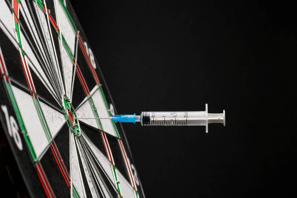Syringes in dartboard stock photo