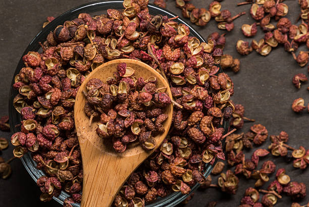 Szechuan Peppercorns in Wooden Spoon With Glass Bowl stock photo
