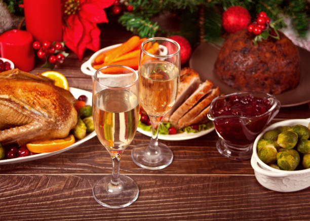 Table served for thanksgiving or Christmas dinner. Two glasses of wine or champagne. Stuffed roasted turkey, pudding and ham. Traditional celebrating holiday. Top view. stock photo