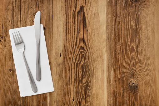 Table setting on rustic wood background - napkin, fork and knife with large copy space