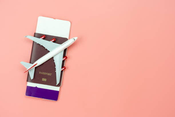 Table top view accessory of accessory travel in holiday background concept.Flat lay of airplane with passport and boarding pass ticket on modern rustic pink paper at home studio office desk.copy space stock photo