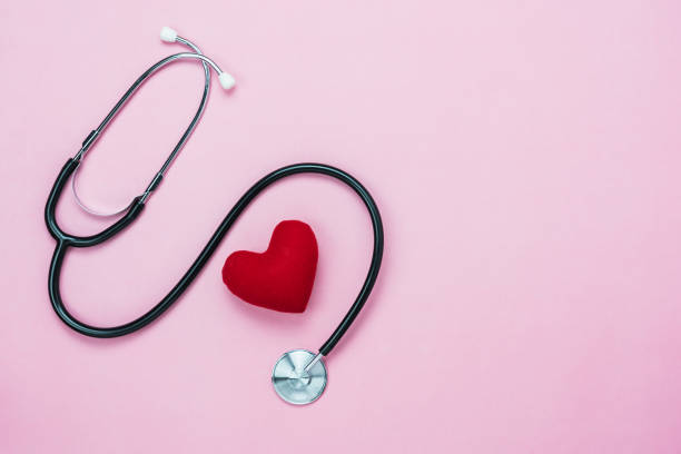 Table top view aerial image of accessories healthcare & medical with Valentines day background concept.telescope with colorful heart shape on pink paper.Flat lay items for doctor using treat patient. stock photo