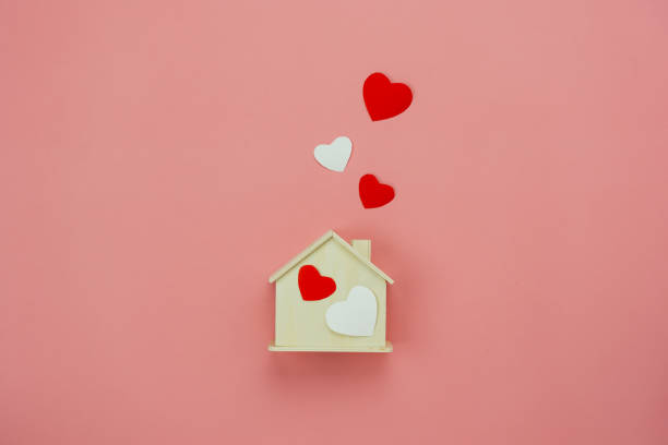 Table top view aerial image of decoration valentine's day background concept.Flat lay essential items colorful pastel love shape with wooden house on modern rustic pink paper.Mock up creative design. stock photo