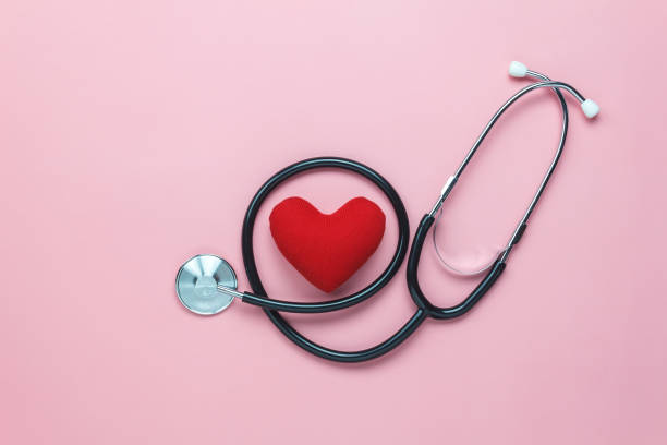 Table top view shot of arrangement equipment medical background concept.Red heart & stethoscope on modern rustic pink paper.An idea essential accessories for doctor for  care patient  in hospital. stock photo