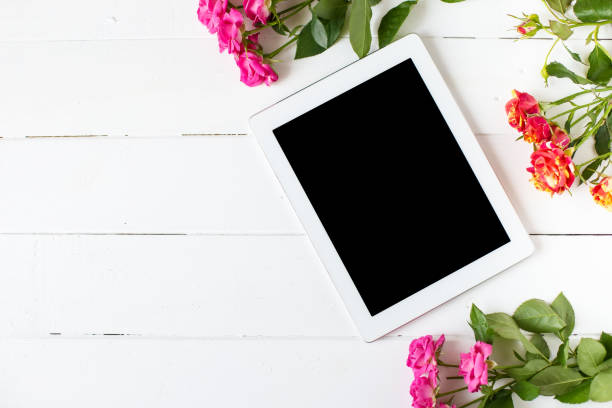 Tablet, roses on the table. Women's things Fashion womens desk Top view stock photo