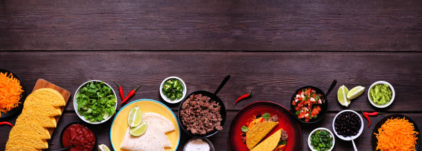 Taco bar bottom border with assorted ingredients on a dark wood banner background. Copy space. stock photo
