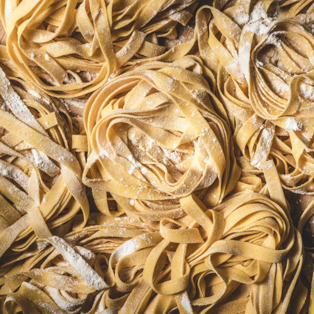 Tagliatelle italian fresh pasta background. Square format  uncooked pasta stock pictures, royalty-free photos & images