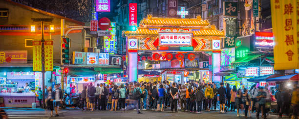Taipei crowds of people Raohe St Night Market panorama Taiwan Crowds of shoppers and tourists at the neon lit entrance to Raohe Street Night Market in central Taipei, Taiwan’s vibrant capital city. night market stock pictures, royalty-free photos & images