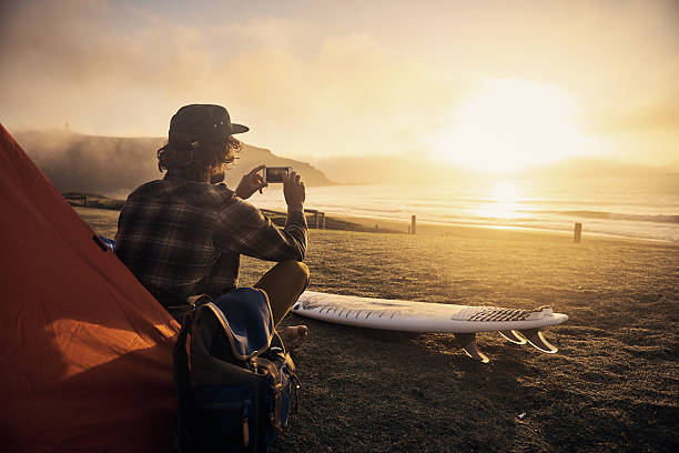 Take some time to yourself Shot of a surfer by his tent while waiting for the perfect wave getting away from it all photos stock pictures, royalty-free photos & images