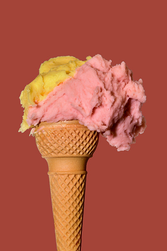 Takeaway ice cream cone with strawberry and lemon flavor on dark pink background