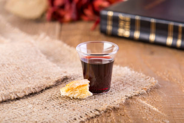 Taking Communion Taking Communion. Cup of glass with red wine, bread and Holy Bible on wooden table close-up. Focus on bread chalice photos stock pictures, royalty-free photos & images