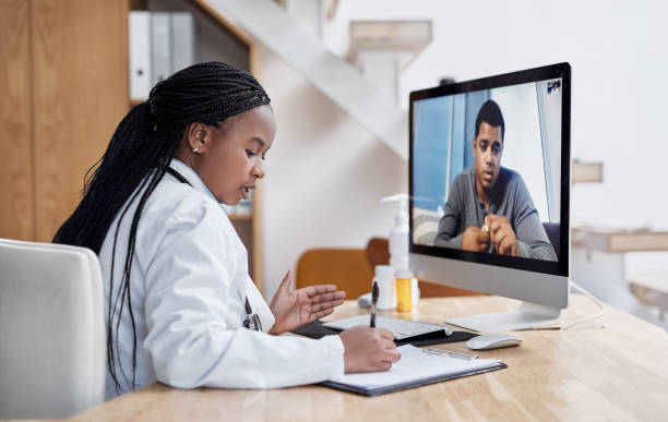 Taking notes during her virtual consult Shot of a young doctor writing notes during a video call with a patient on a computer telemedicine stock pictures, royalty-free photos & images