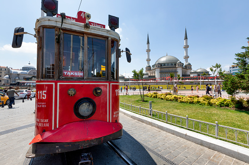 Istanbul, Turkey - May 31, 2022: Nostalgic Trams passing through Crowded Istiklal street in a sunny day in Taksim, Beyoğlu, Istanbul, Turkey. Crowd of diverse People walking along Istiklal Caddesi street most popular shopping and entertainment place during weekends