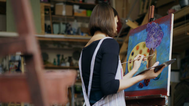 Talented young woman artist painting picture on canvas in art-class stock photo