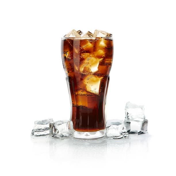 Tall glass of brown drink overflowing with ice cubes stock photo