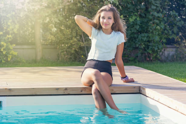 Tanned girl is isitting on the edge of the pool stock photo
