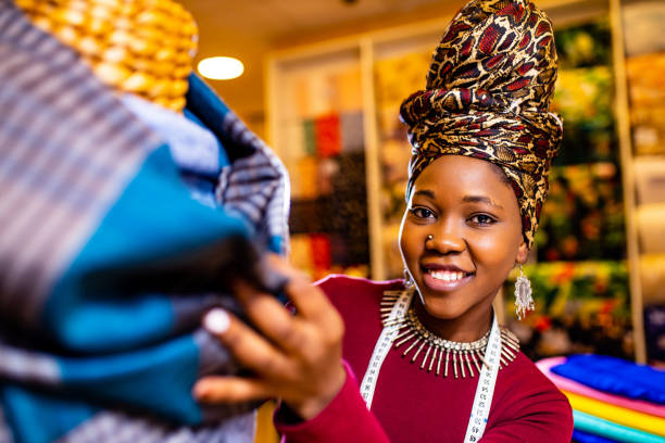 tanzanian woman with snake print turban over hear working in fabrics shop stock photo