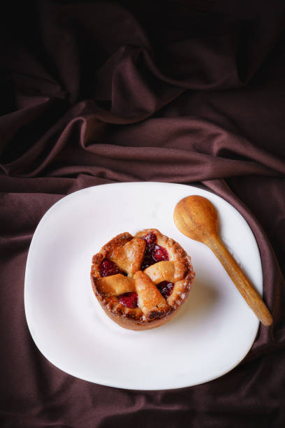 tartlet or pancake filled with delicious homemade strawberry jam on a white plate with a wooden spoon stock photo