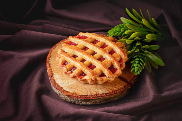 tartlet or tart filled with homemade delicious strawberry jam on a brown wood and cloth for a snack stock photo