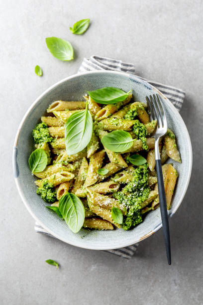 Tasty appetizing pasta with pesto sauce Tasty appetizing wholegrain pasta with pesto sauce, parmesan cheese and basil served on plate on grey background. noodles stock pictures, royalty-free photos & images