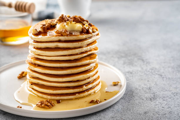 Tasty breakfast. Homemade pancakes with crushed walnut, honey or maple syrup on grey background. stock photo