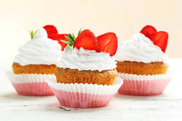 Tasty cupcake with strawberry on white wooden background stock photo