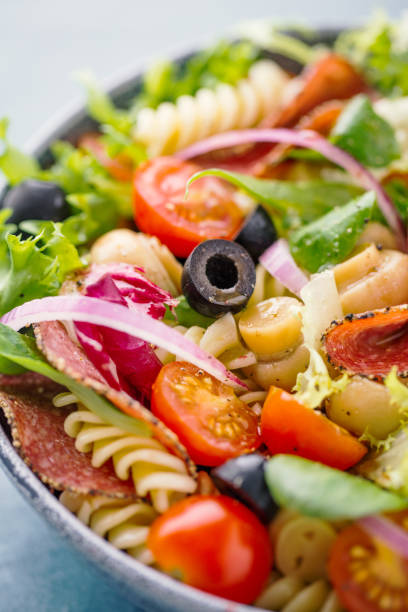 Tasty italian antipasto salad Tasty appetizing antipasto italian salad with salami, olives, vegetables and pasta in bowl. Lactose free. Closeup. antipasto stock pictures, royalty-free photos & images