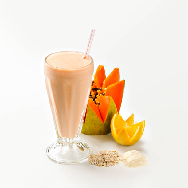 Tasty papaya and orange smoothie Glass with tasty papaya and orange smoothie on white background, with ingredients aside on white background papaya smoothie stock pictures, royalty-free photos & images