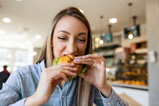 Young blond girl eating a small sandwich