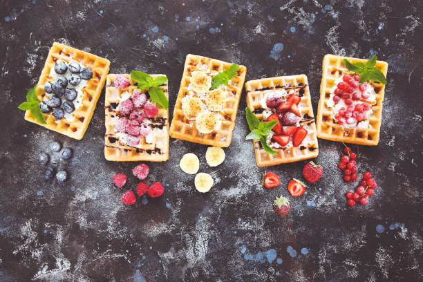 Tasty waffles with fresh berries and whipped cream on black background stock photo
