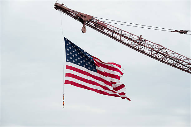 Tattered American Flag Flies From Construction Crane stock photo
