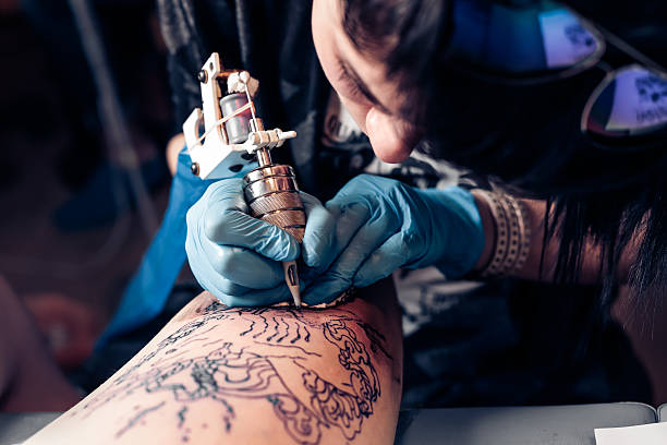 Tattoo artist demonstrates the process of tattoo Close up tattoo artist demonstrates the process of getting black tattoo with paint. Master works in black sterile gloves. Master of tattoo fill circuit tattoo. tattoo stock pictures, royalty-free photos & images