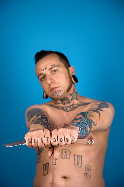 Tattooed man holding knife. Barechested Caucasian young adult man with tattoos and piercings holding knife. mutton chops stock pictures, royalty-free photos & images