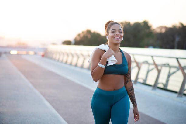 getatoeëerde jonge vrouw die naar huis gaat na het rennen in de ochtend - wandelen lichaamsbeweging stockfoto's en -beelden
