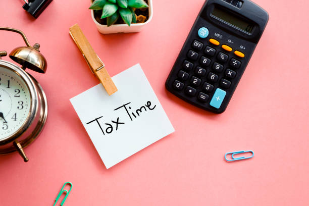 het concept van de belastingtijd op kleverige nota, calculator en klok op roze achtergrond - belastingdienst stockfoto's en -beelden